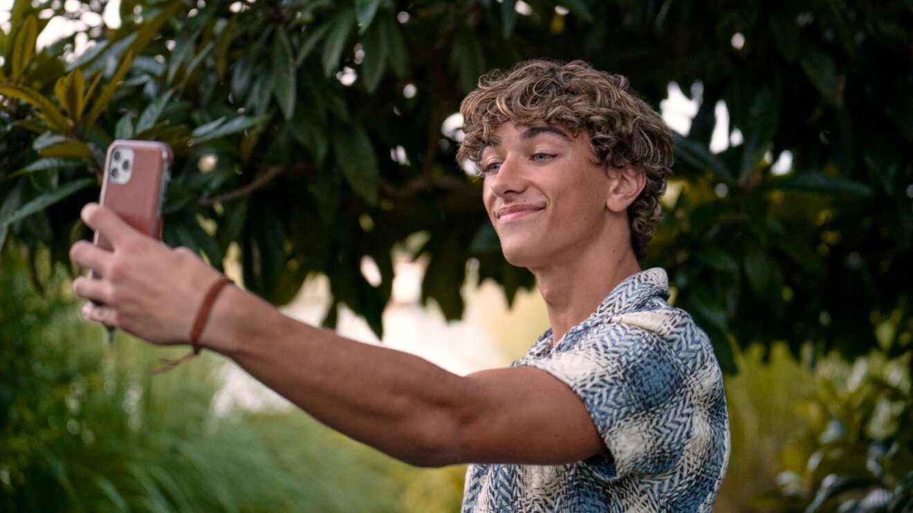 Casually dressed Jeremiah Fisher (Gavin Casalegno) capturing self-portrait in nature