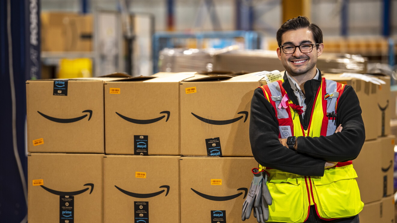 an amazon employee is standing in front of a pile of amazon boxes