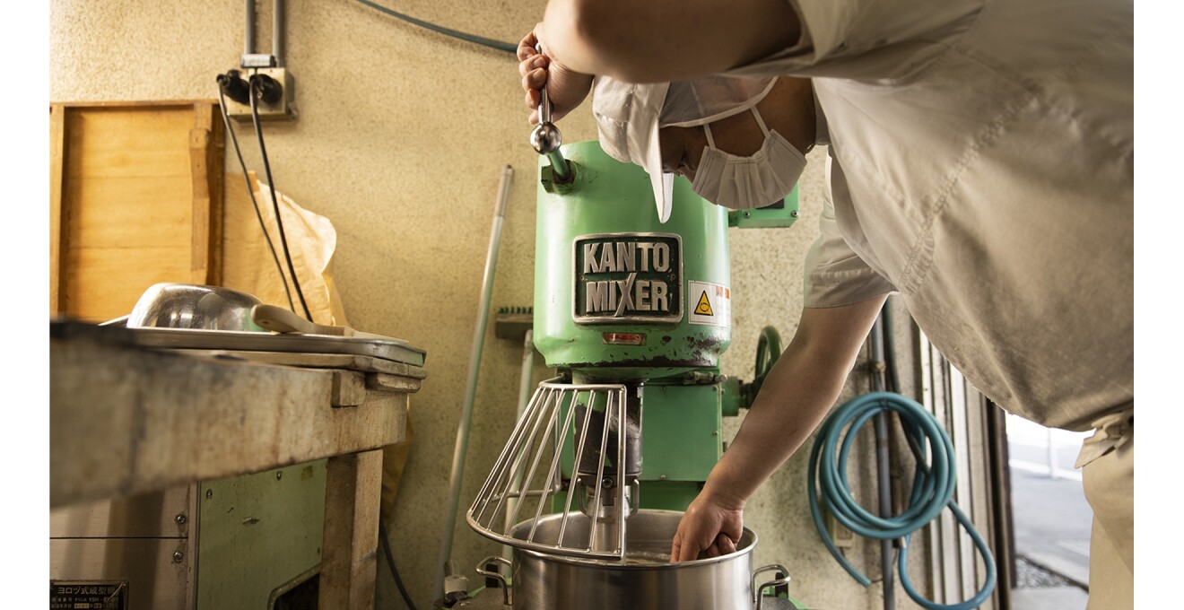 マスク・帽子・エプロンをした職人がミキサーで製造作業をしている写真