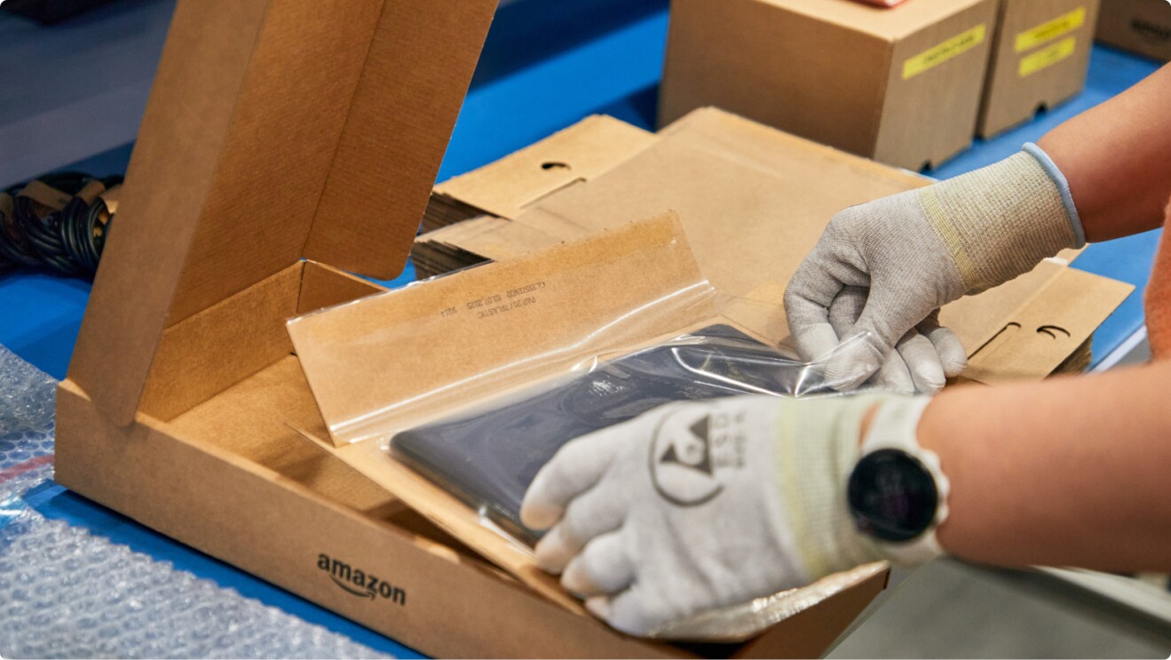 Worker in protective gloves packaging item in Amazon box