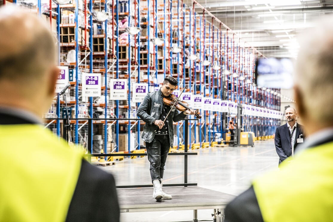 Geiger Noah mit seiner Geige, im Hintergrund sieht man verschwommen Hochregale