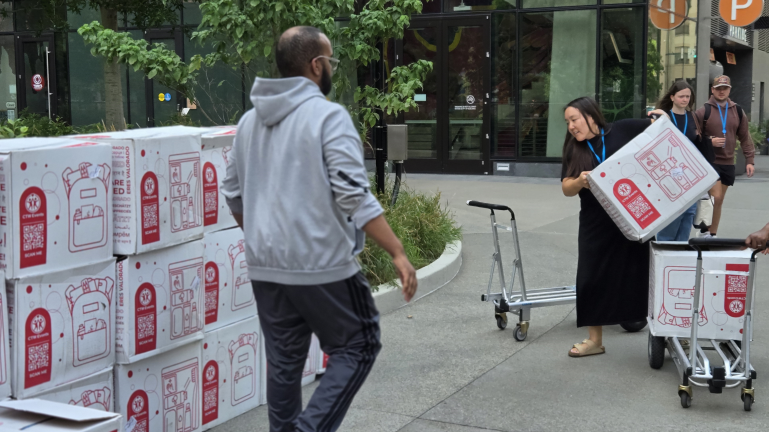 People unloading boxes with robot illustrations outside a building
