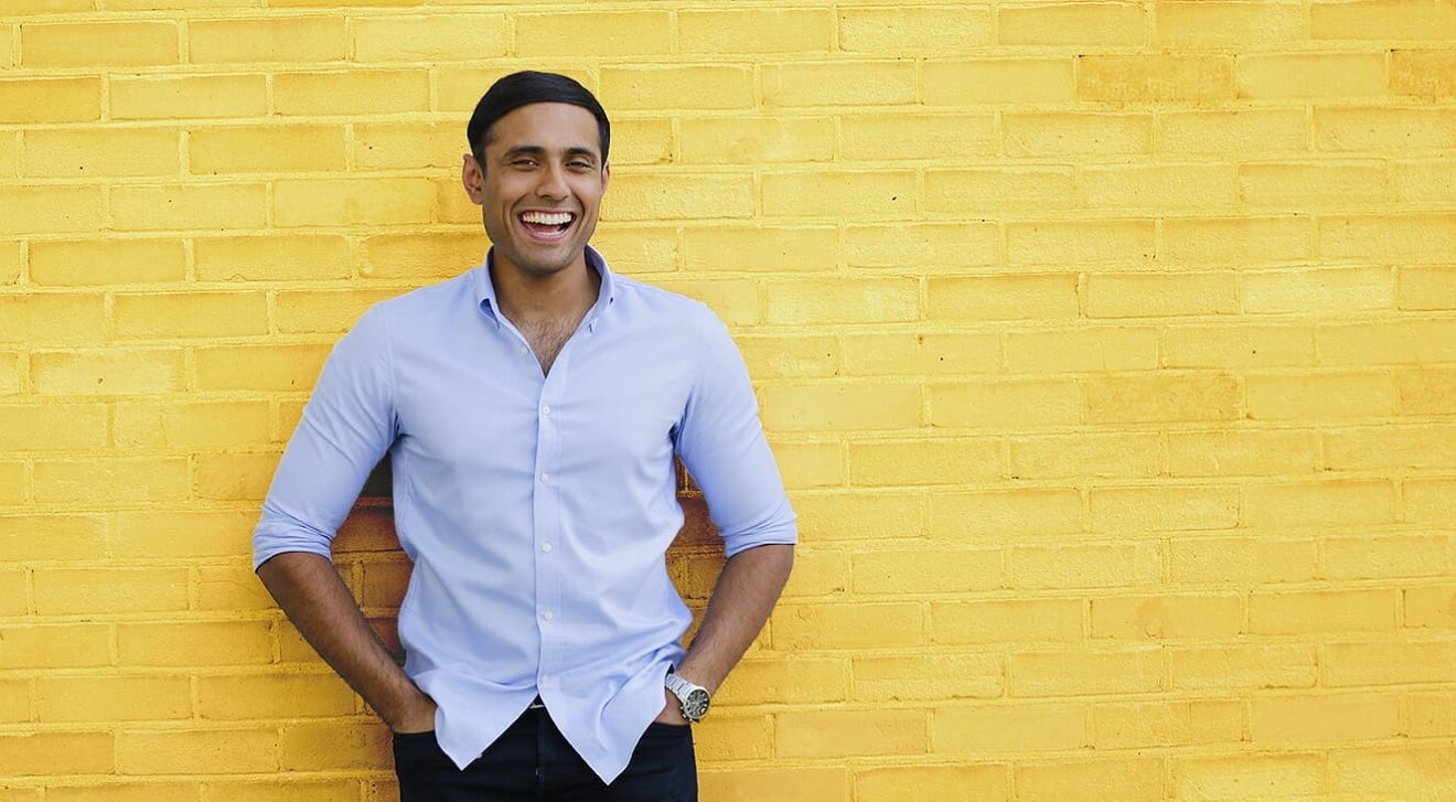 Dhruvin Patel, Founder of Ocushield, standing in front of a yellow brick wall. 