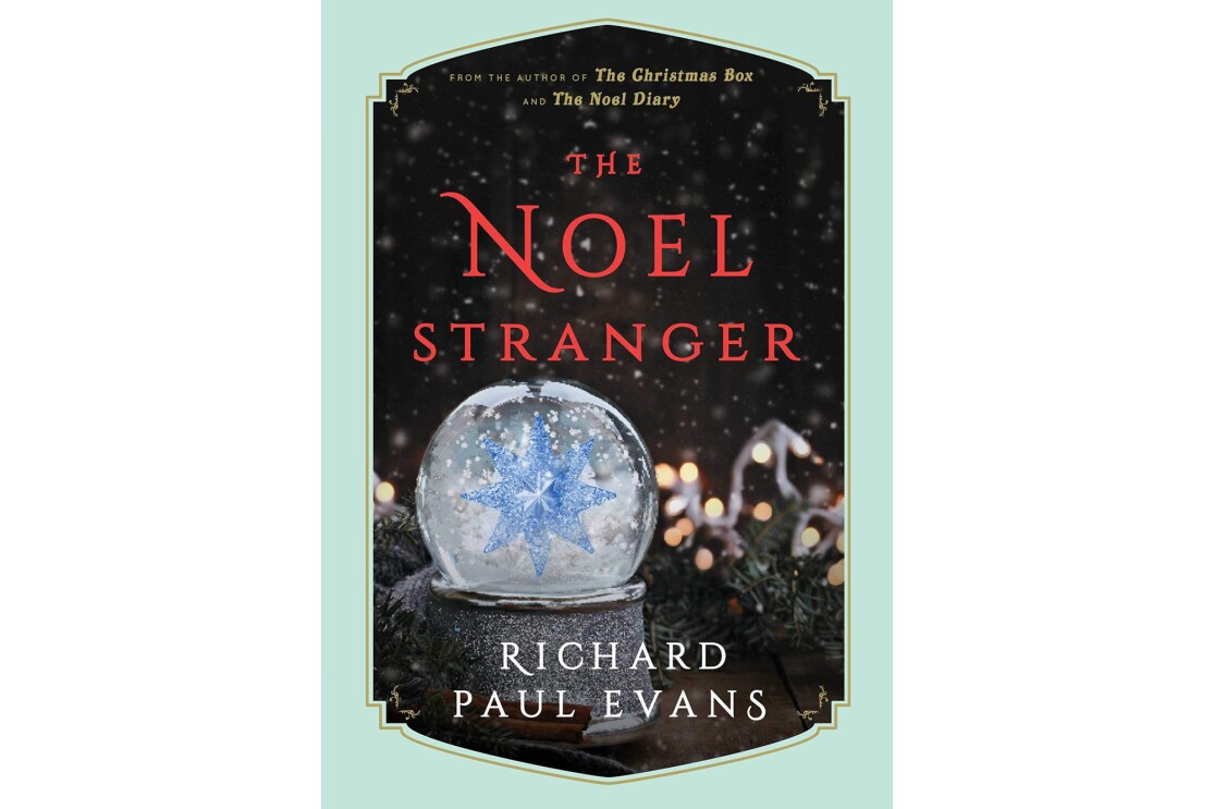 Book cover for "The Noel Stranger" shows a snow globe in the foreground with snow falling around a large crystal snowflake. In the background is garland, with Christmas lights, snow falls on the scene. The title is in red, with the author's name in white.