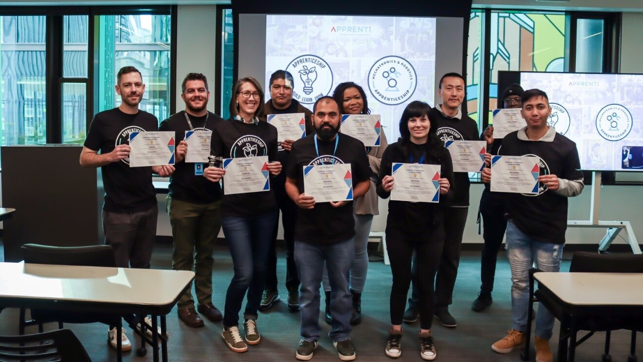 An image of employees holding certificates from an Amazon apprenticeship program.