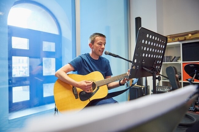 Amazon employee playing a guitar to colleagues at Scotland development centre