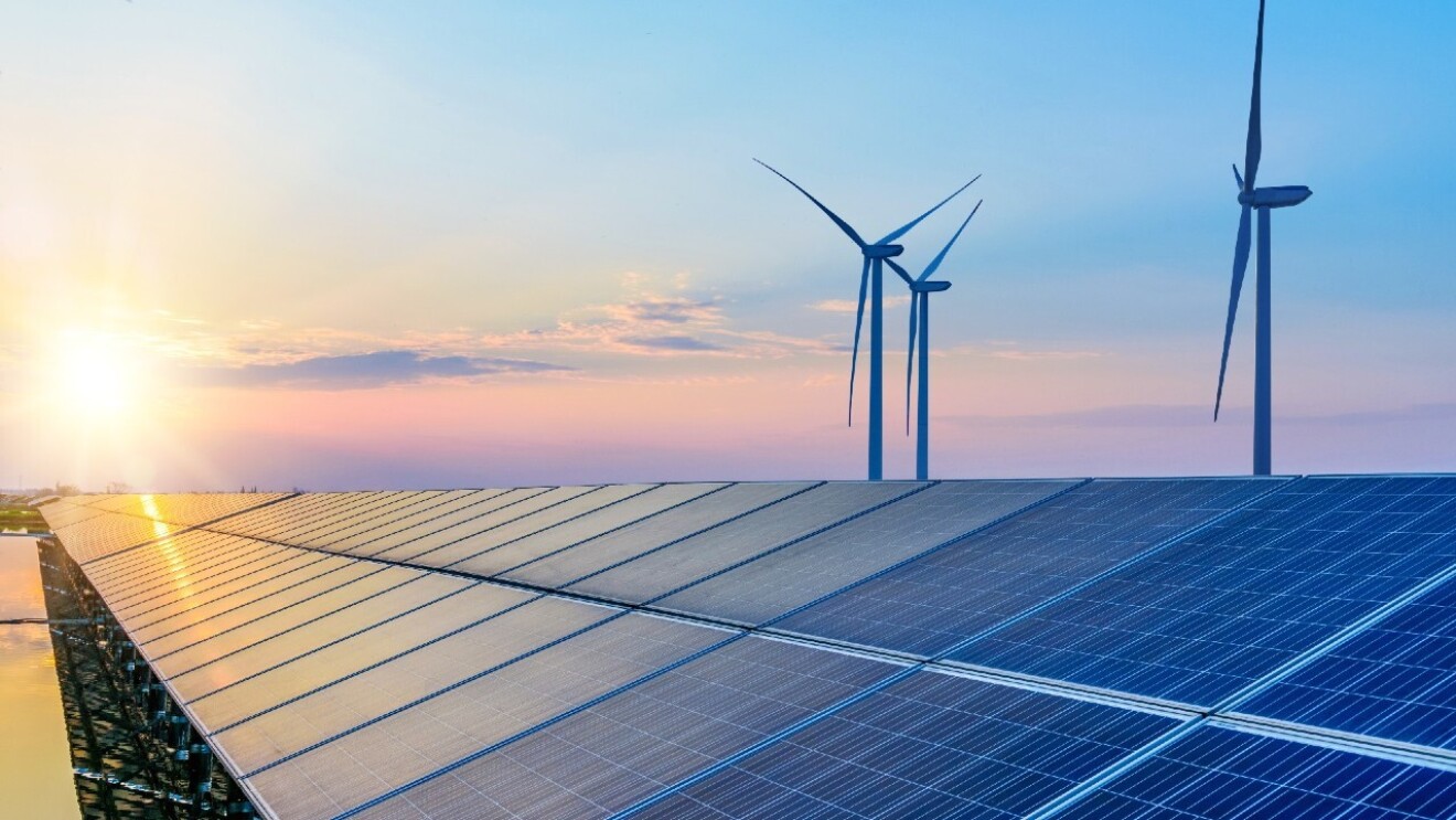 The sun sets on a wind and solar panel farm.