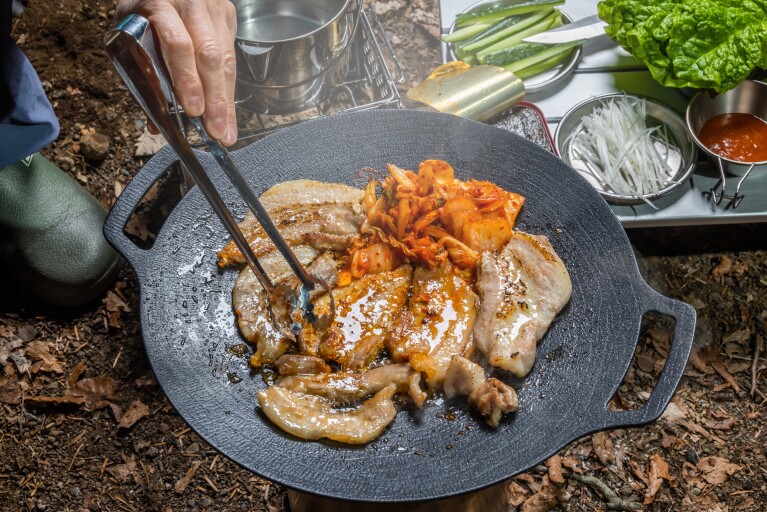 薄い鉄板製のグリドルの上で焼かれているお肉やキムチ