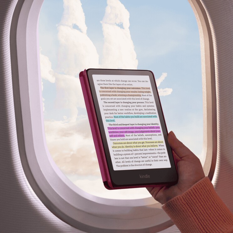 Kindle e-reader displaying text, held against airplane window
