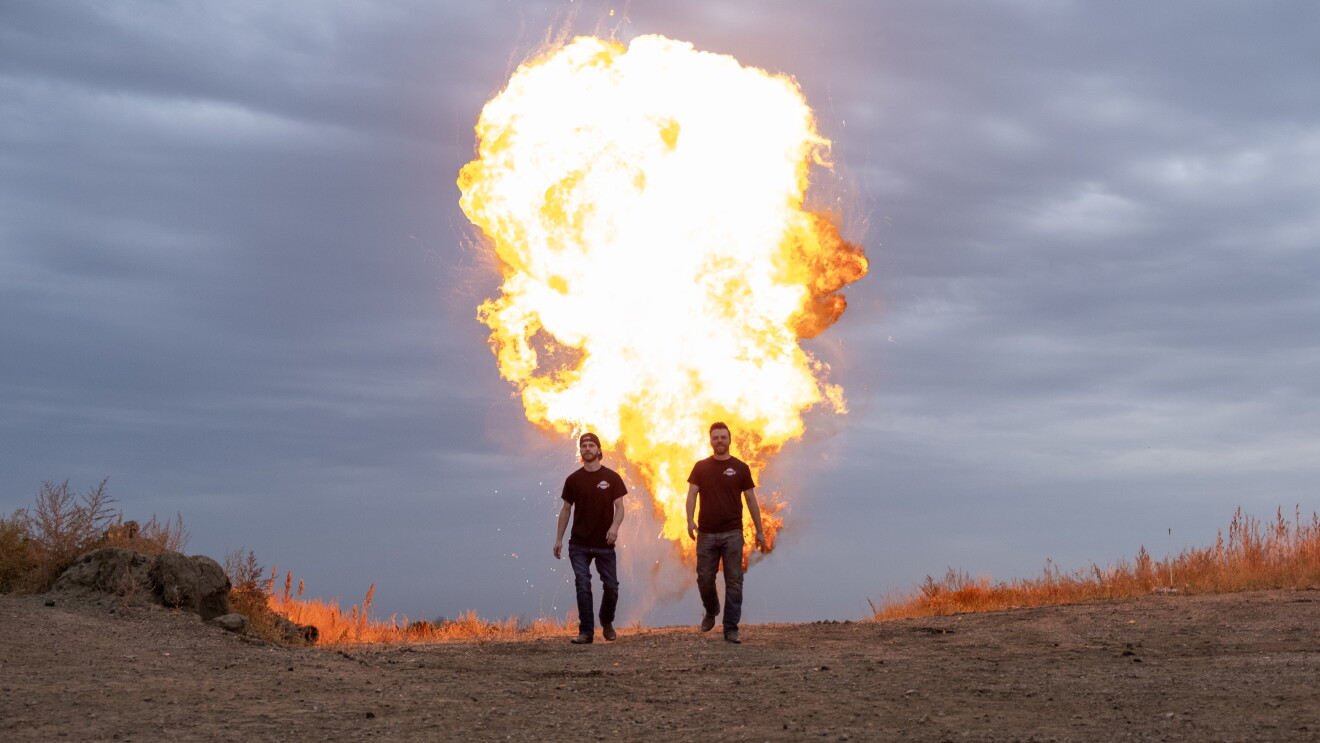three men walking away from a fire