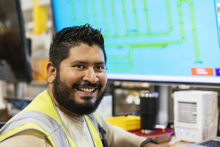 Amazon employee with his back turned to a computer and smiling.
