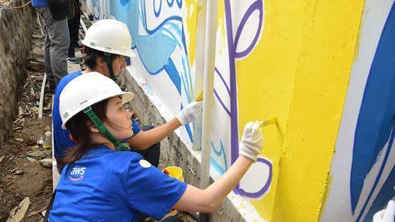 Volunteers paint walls of a clean water facility as part of an AWS water positive project in Karawang, West Java, Indonesia