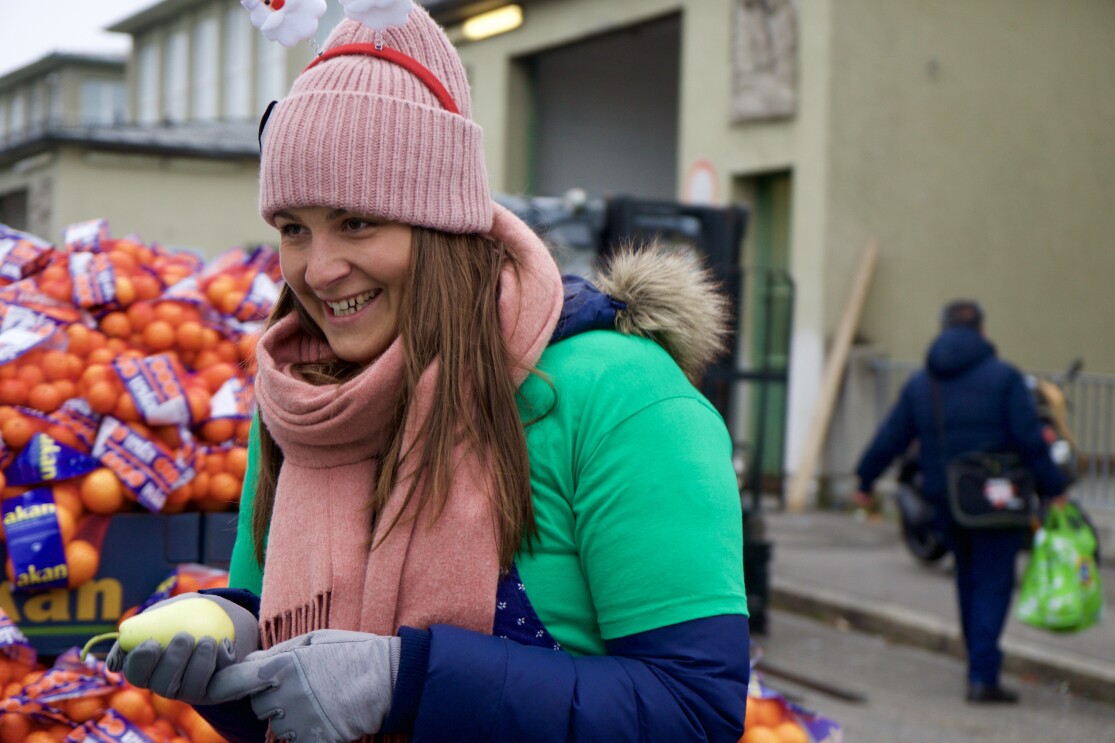 Eine junge Frau im grünen Shirt bei der Ausgabe von Obst