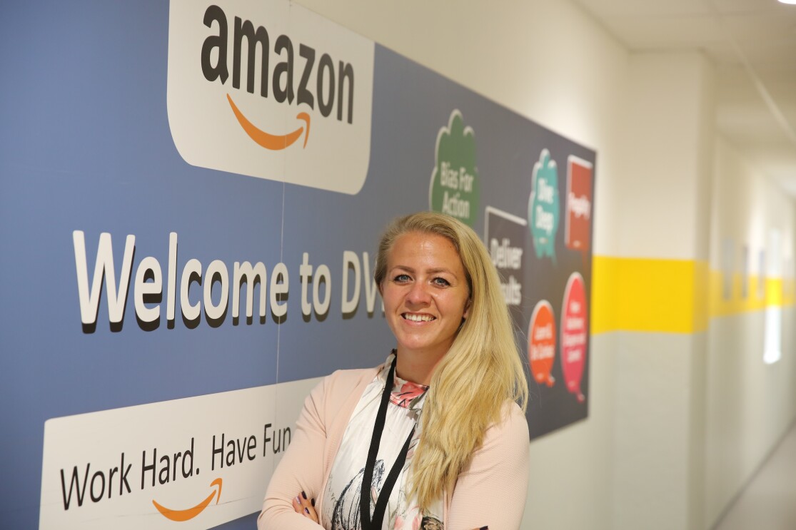 Eine blonde Frau vor einem Amazon Plakat