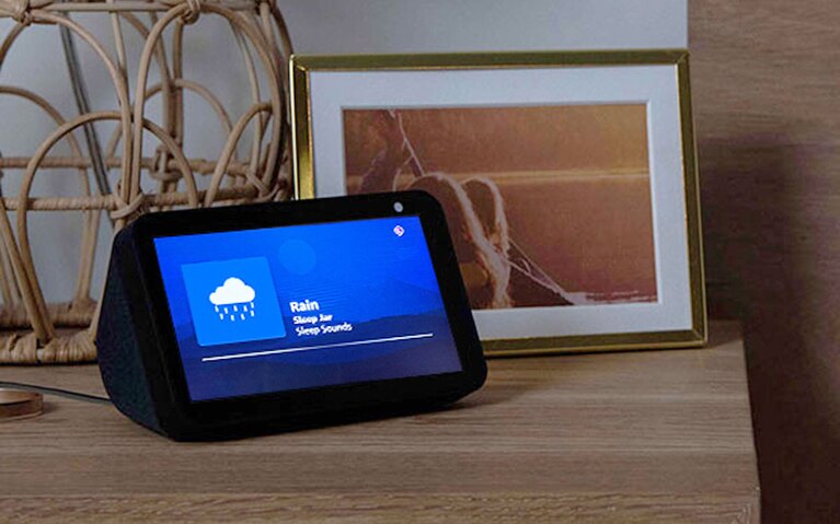 An image of an Amazon Echo Show device sitting on a nightstand showing the Rain Sleep Jar feature.