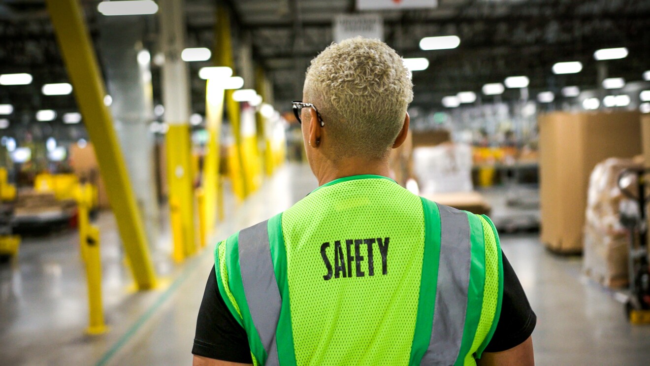 A person wearing a safety vest in a warehouse.