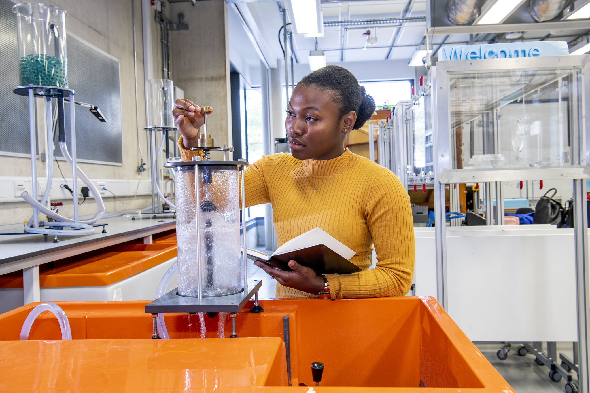 Female engineer wearing yellow jumper and studying liquid