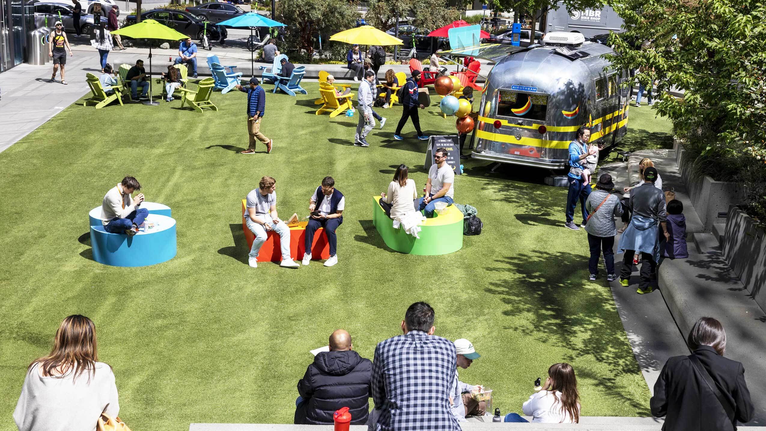 People sit on the field outside Day 1/the Spheres.