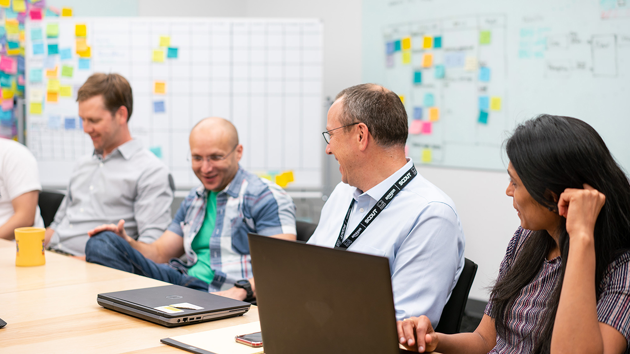 Four people sit at a table in an Amazon office, as they