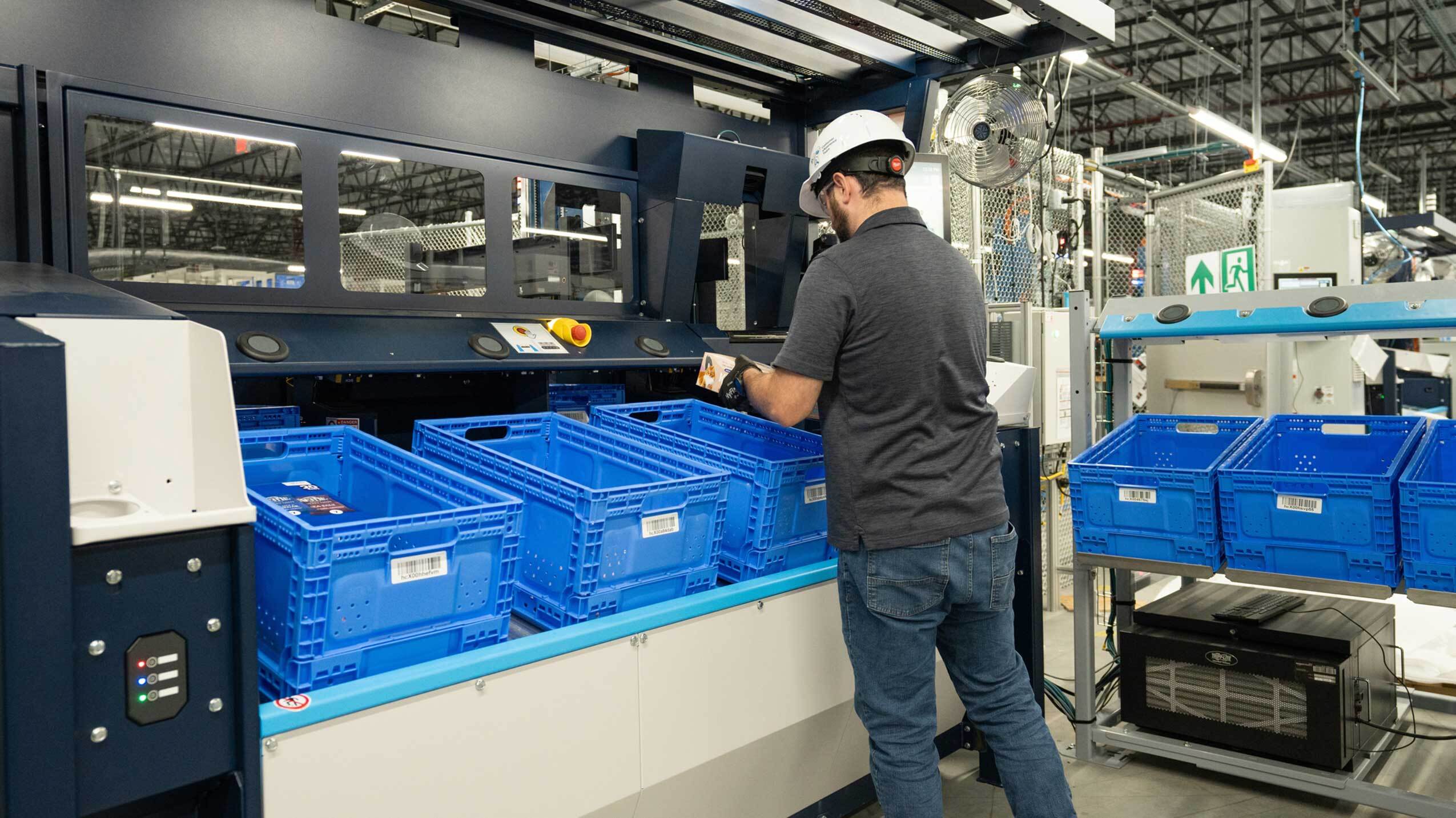 An image of an employee in a hard hat and the new robotic solution that will support workplace safety and help Amazon deliver to customers faster