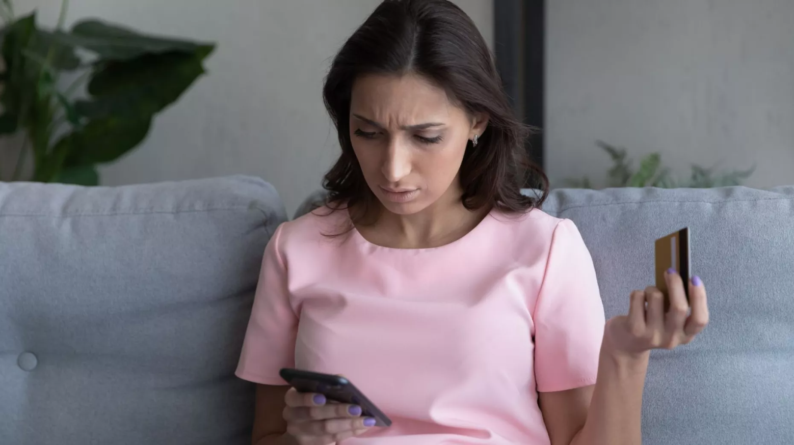A woman holding her bank card and looking at her phone
