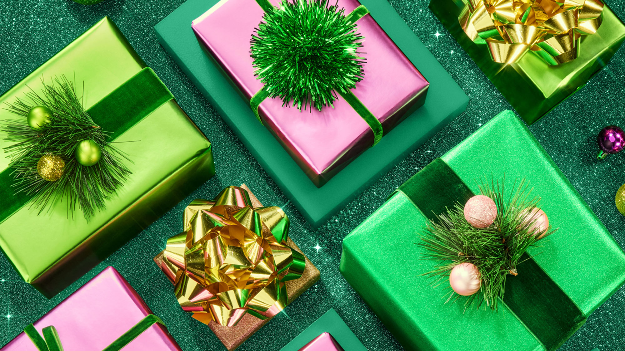 Festive gift boxes in green and pink with gold bows and pine decorations