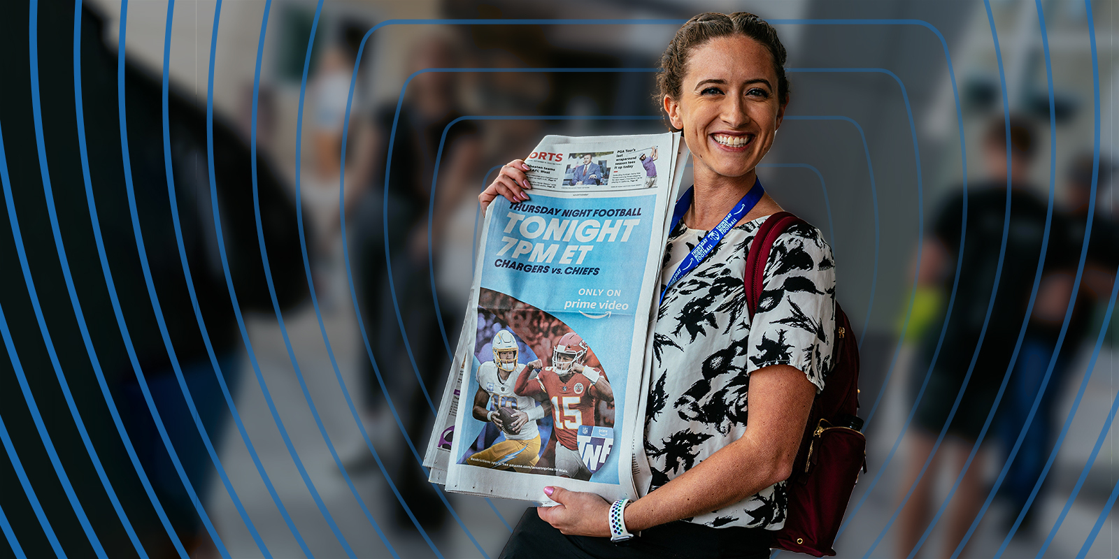 Gigi Clark smiles for a photo while holding up a news paper announcing Thursday Night Football