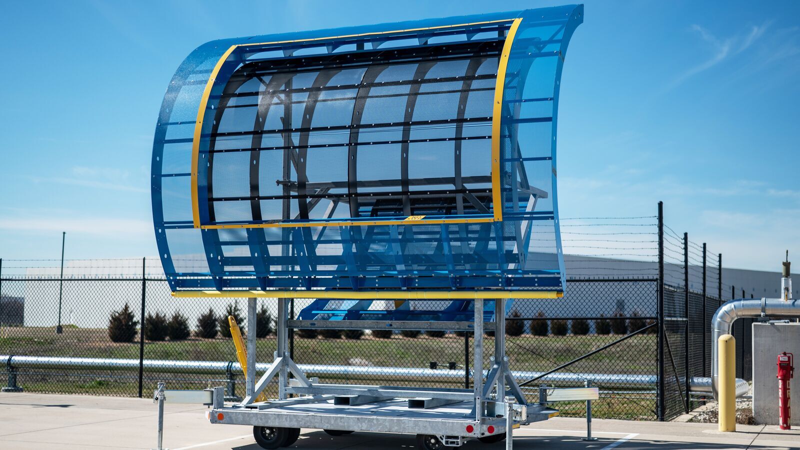 An image of a large, blue structure that looks like a door on the side of the plane. The structure is parked in a cement area outside of the Amazon Air Hub.