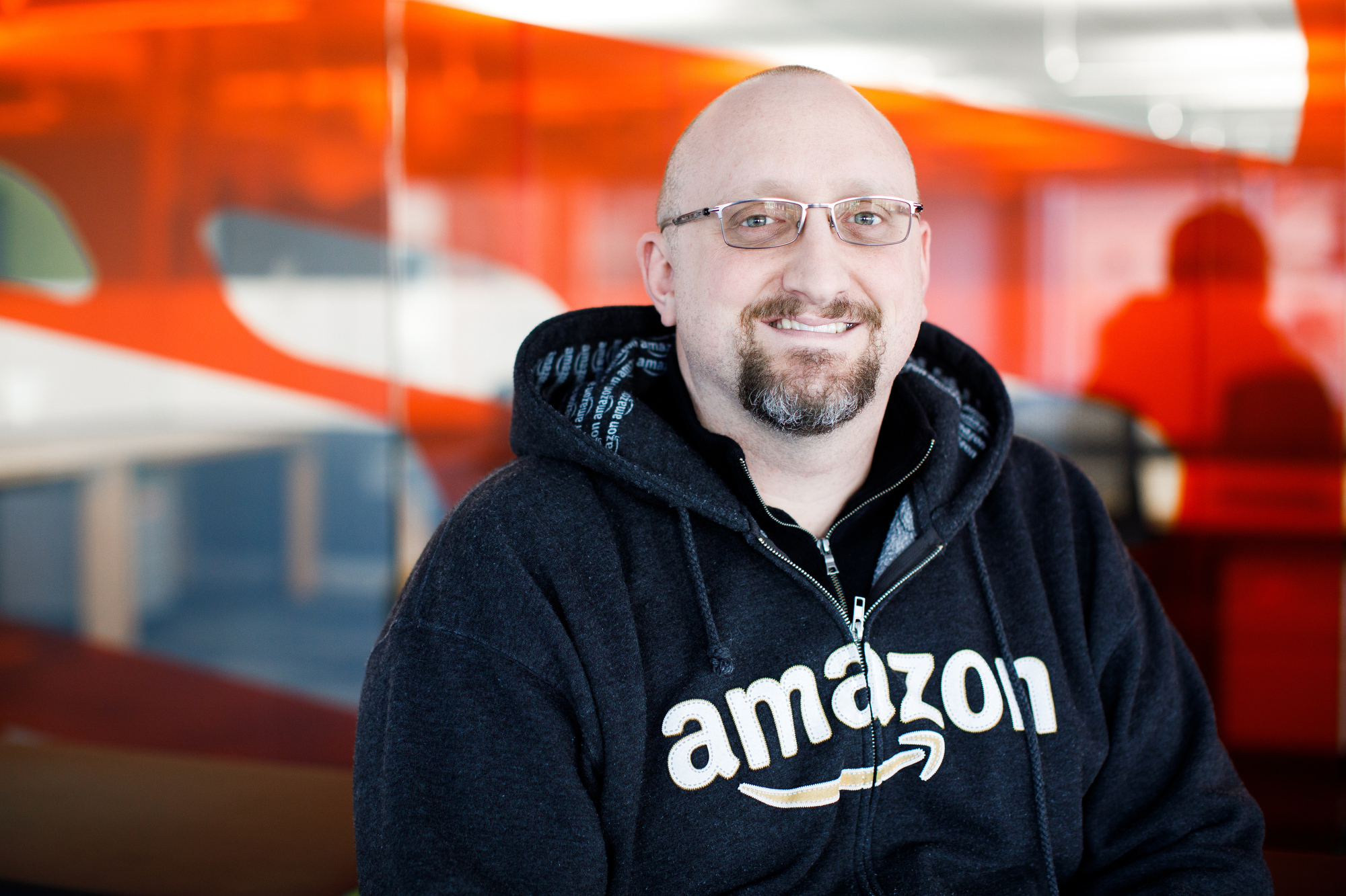 Bill Kaper, PIT10 site leader, smiles into the camera. He is wearing a dark blue hoodie that says amazon. 