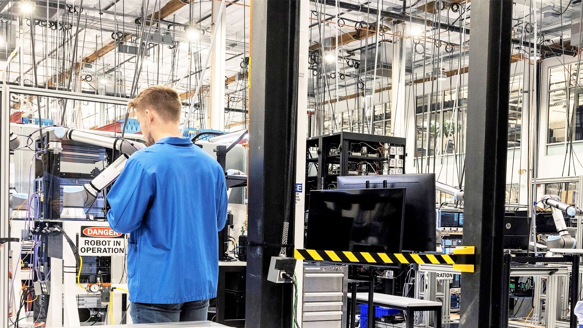 Amazon employee wearing blue lab coat working in a Project Kuiper factory. 