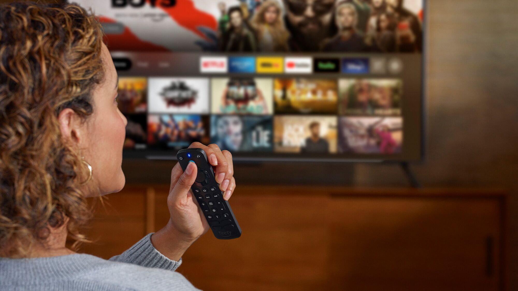 A woman using remote control to browse Fire TV streaming service