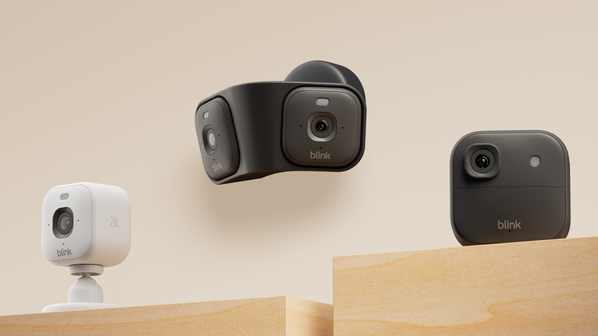 Three Blink security cameras on wooden platforms against beige background
