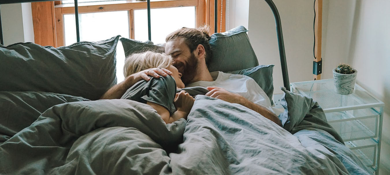 Ein junges Pärchen kuschelt im Bett