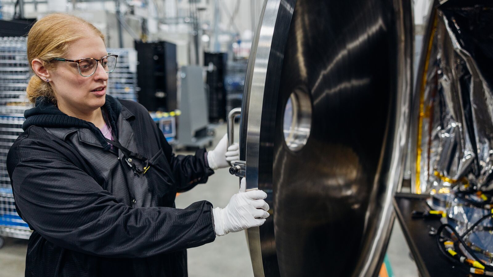 Jessica Hubbell examines satellite hardware inside Amazon Leo's space simulation lab