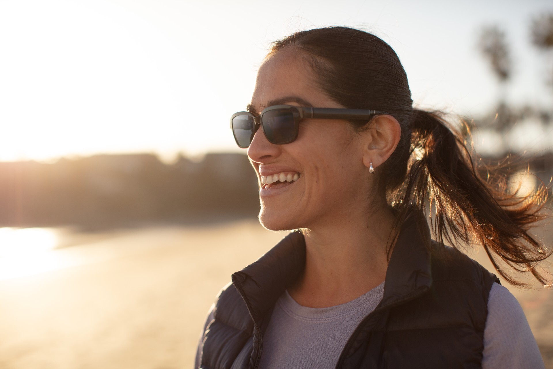 A woman wearing Echo Frames sunglasses while smiling watching the sunrise.