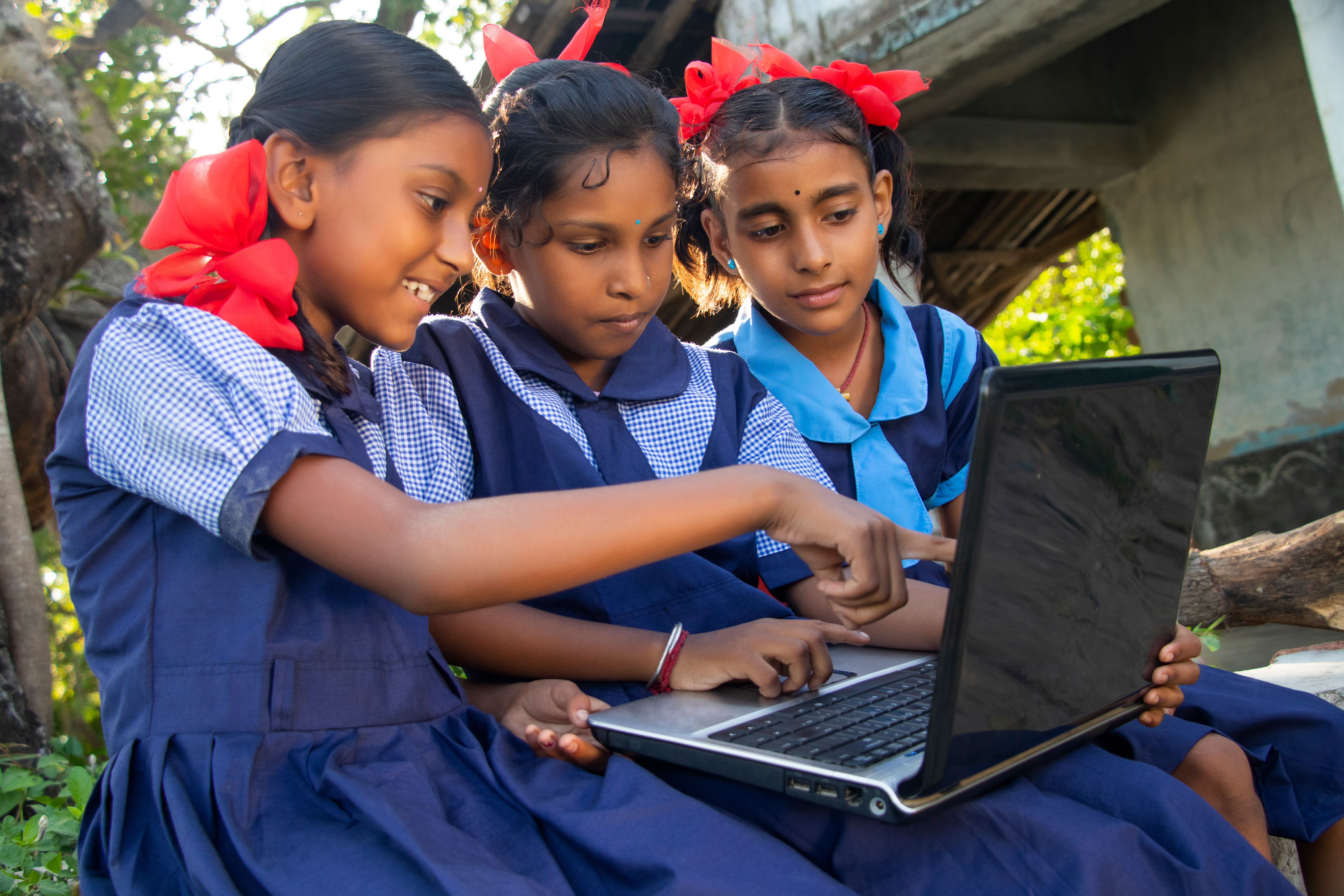 3 School girls sit together watching a laptopm